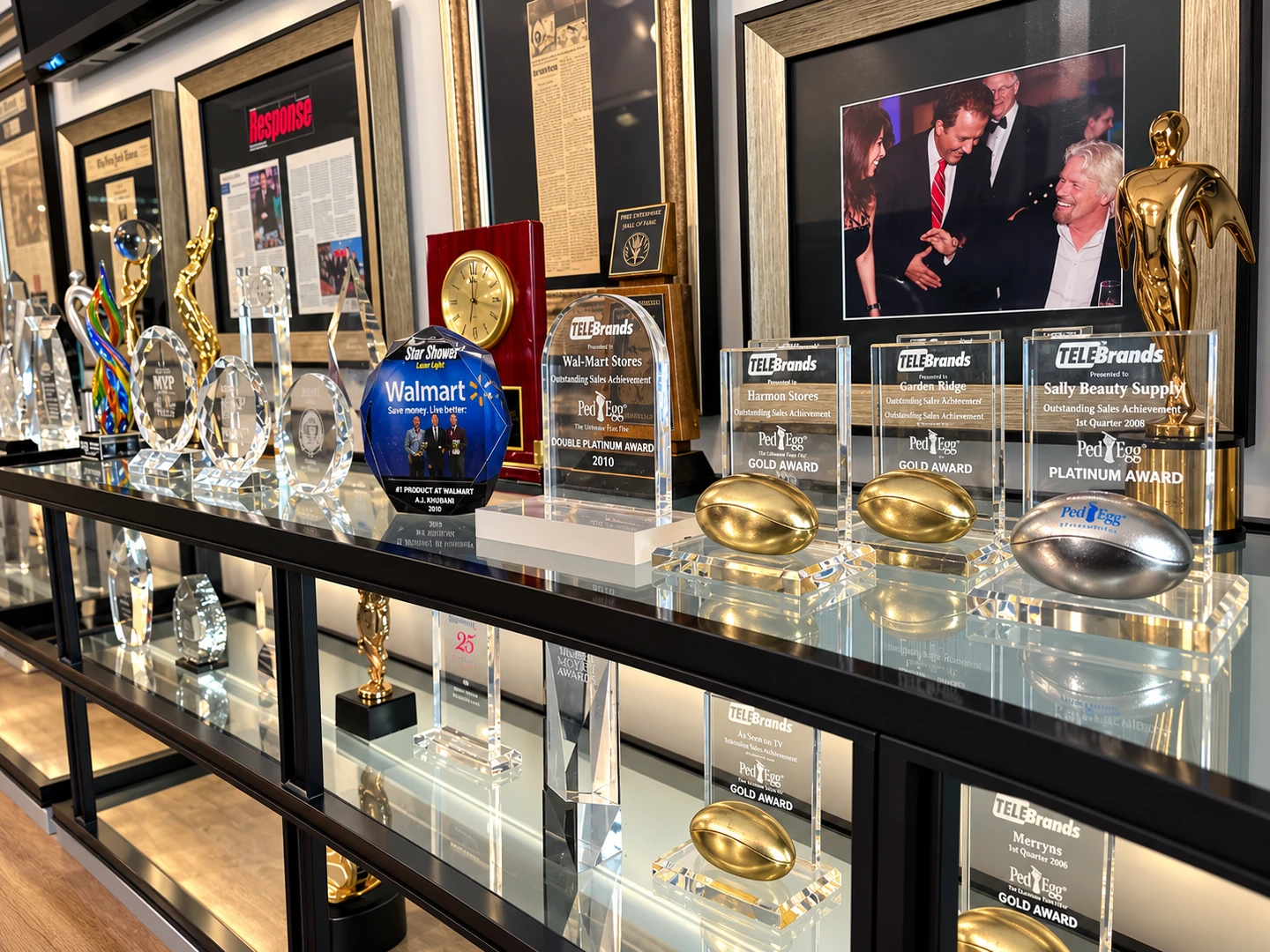 Telebrands award display with PedEgg sales plaques, a Star Shower display piece and framed company coverage