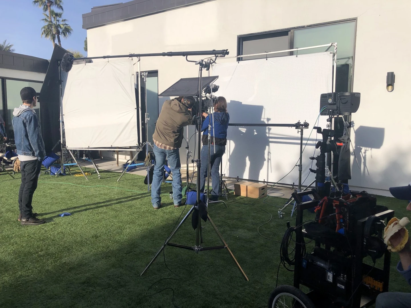 Outdoor production equipment, crew and a large lighting diffusion frame on a lawn