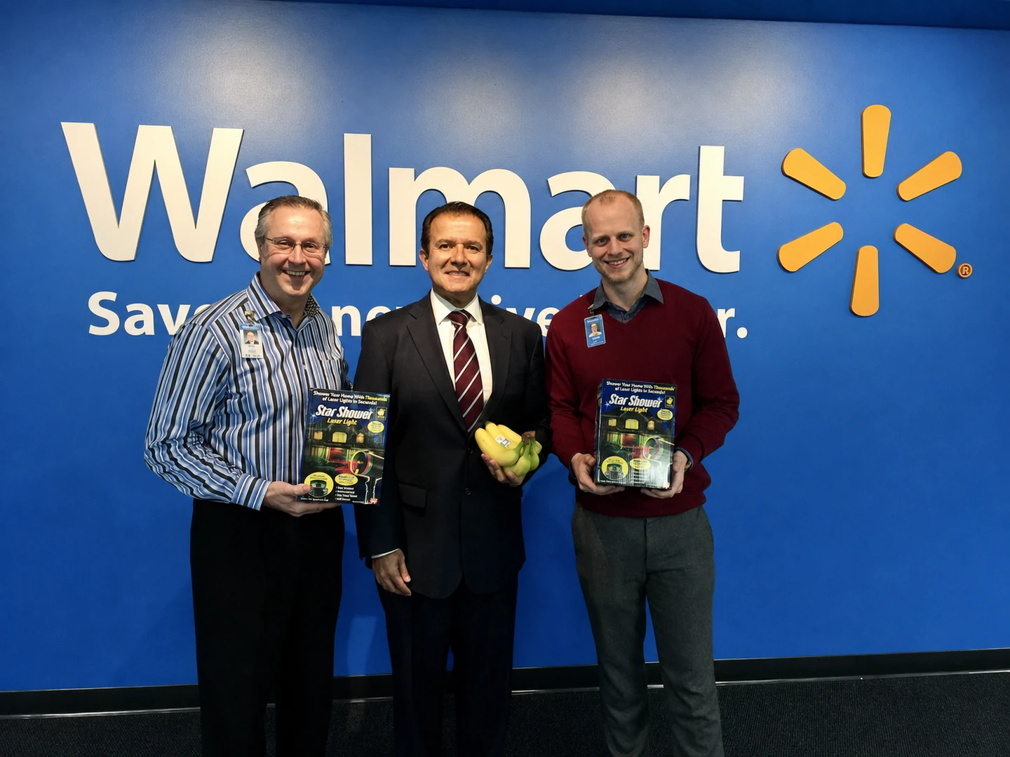 Joe Grady and Griffin Sorenson holding Star Shower boxes, with AJ Khubani holding bananas between them, in front of the Walmart sign